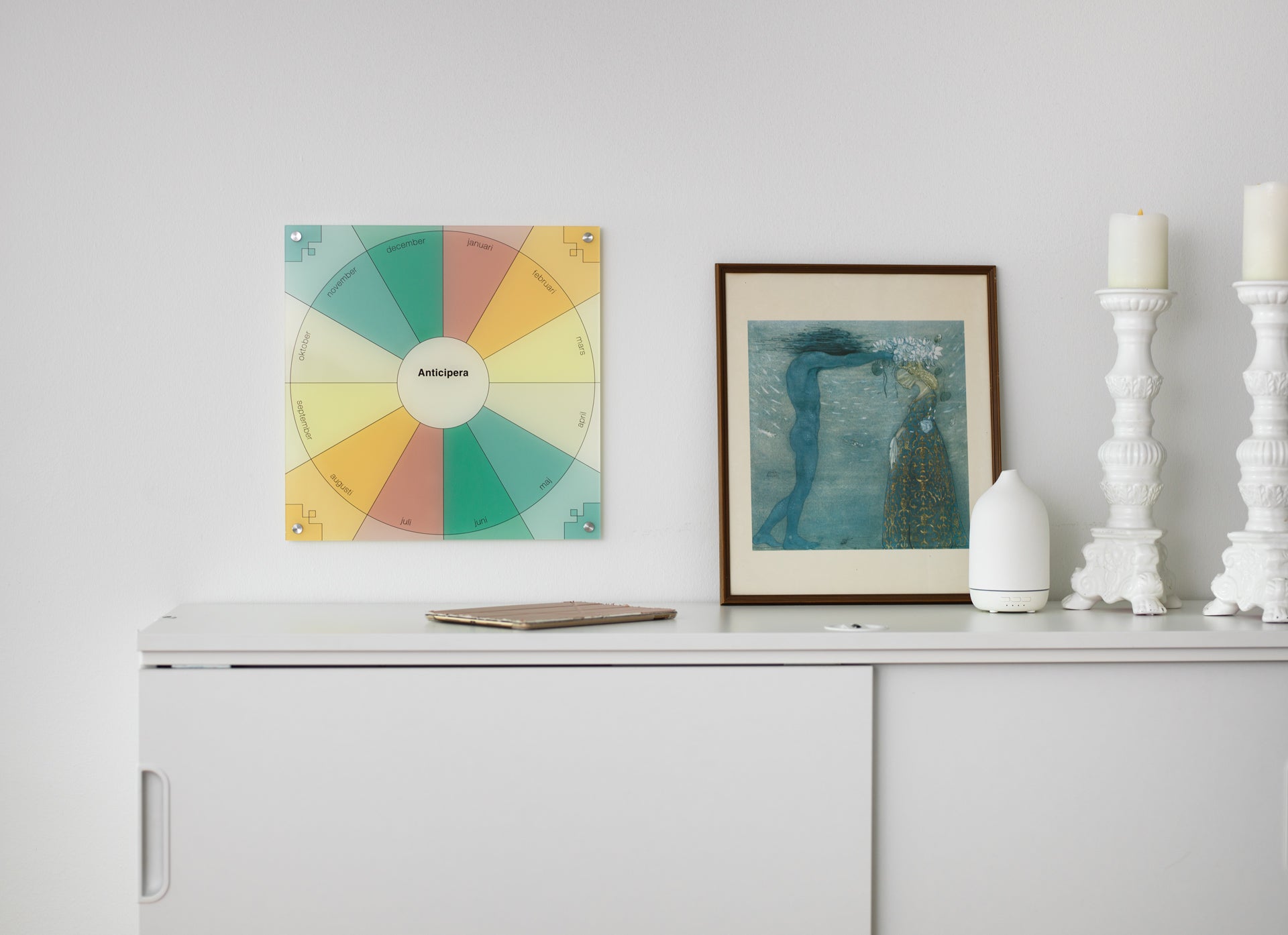 Anticipera Evighetskalender i stilen Emma står på ett arkivskåp från IKEA tillsammans med en John Bauer tavla, två kandelabrar och en diffuser.
