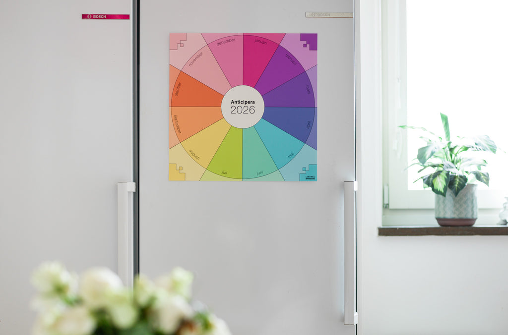 Anticipera väggplanerare i stilen Emelie sitter på ett vitt kylskåp. I förgrunden skymtar lite blommor. 