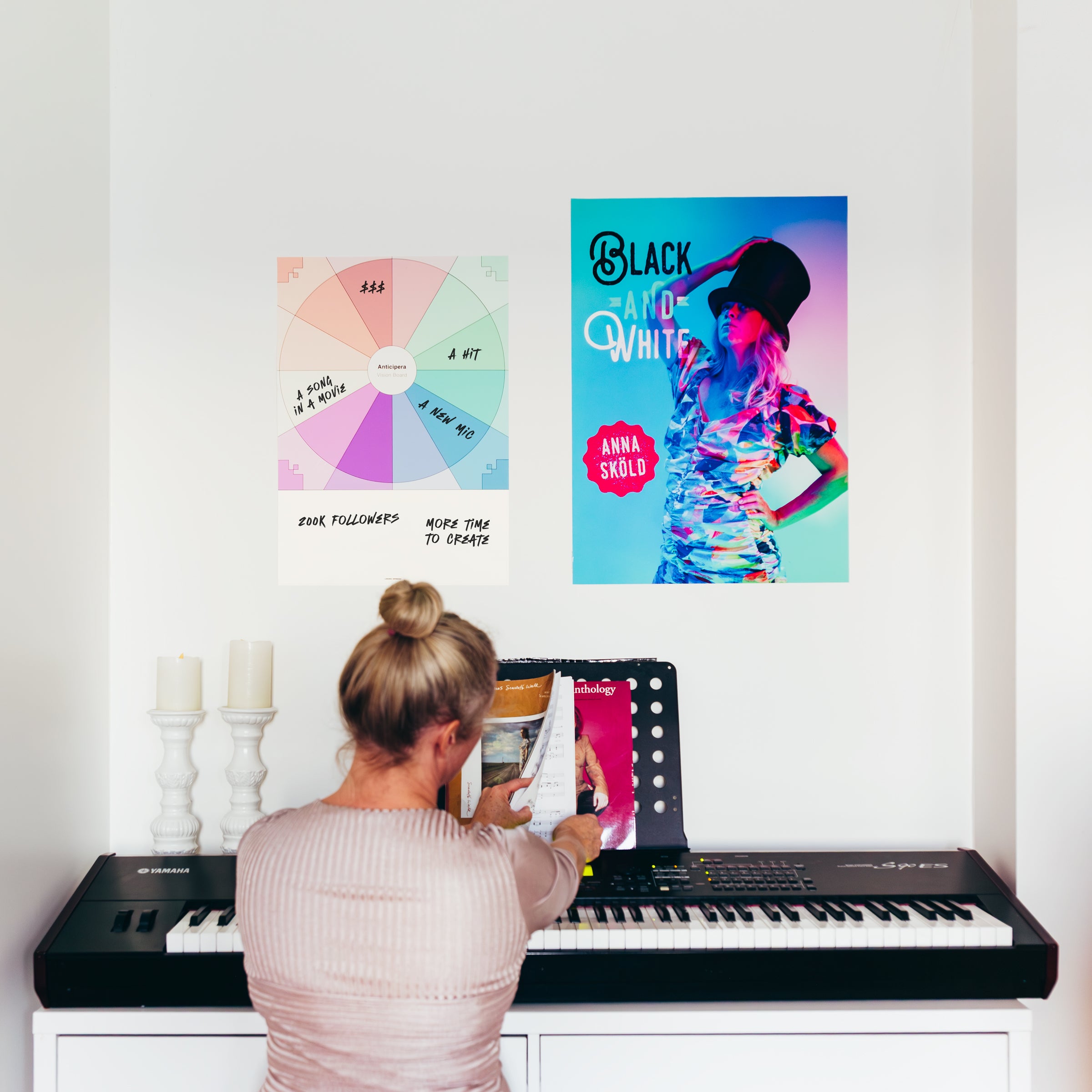 Anticipera Vision Board i stilen Joan med artistdrömmar om att skapa en hit, tjäna pengar, få följare, en sång i en film och en ny mick. Bredvid Vision Boarden finns en affisch för låten Black & White med Anna Sköld. Anna Sköld sitter vid pianot och bläddrar i noter. 