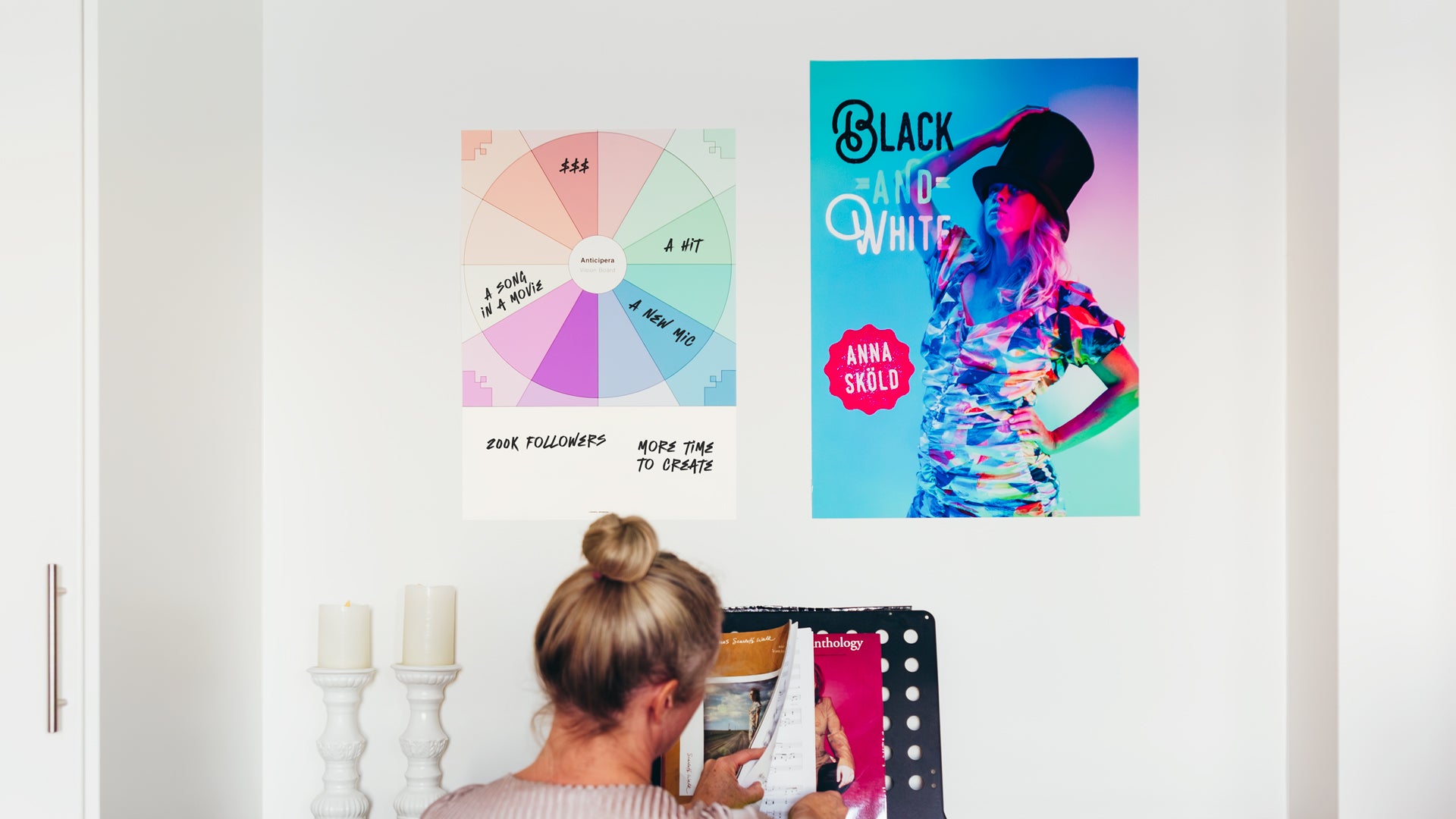 Anticipera Vision Board i stilen Joan med artistdrömmar om att skapa en hit, tjäna pengar, få följare, en sång i en film och en ny mick. Bredvid Vision Boarden finns en affisch för låten Black & White med Anna Sköld. Anna Sköld sitter vid pianot och bläddrar i noter. 